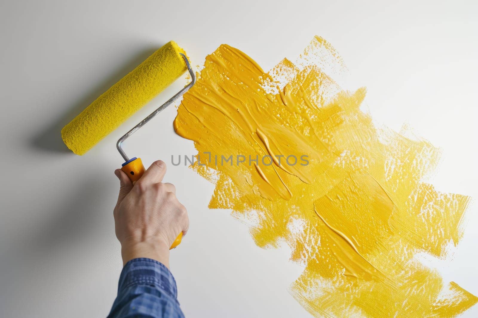 A moment of creativity when a hand with a paint roller paints the wall bright yellow.