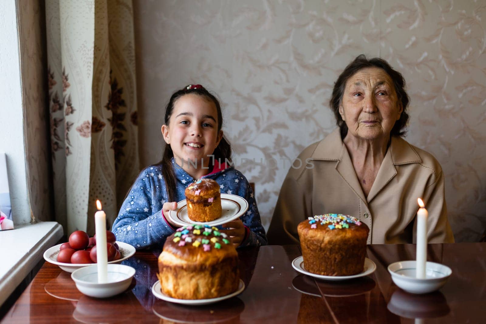 Easter concept. Grandmother with granddaughter are holding Easter eggs at home.