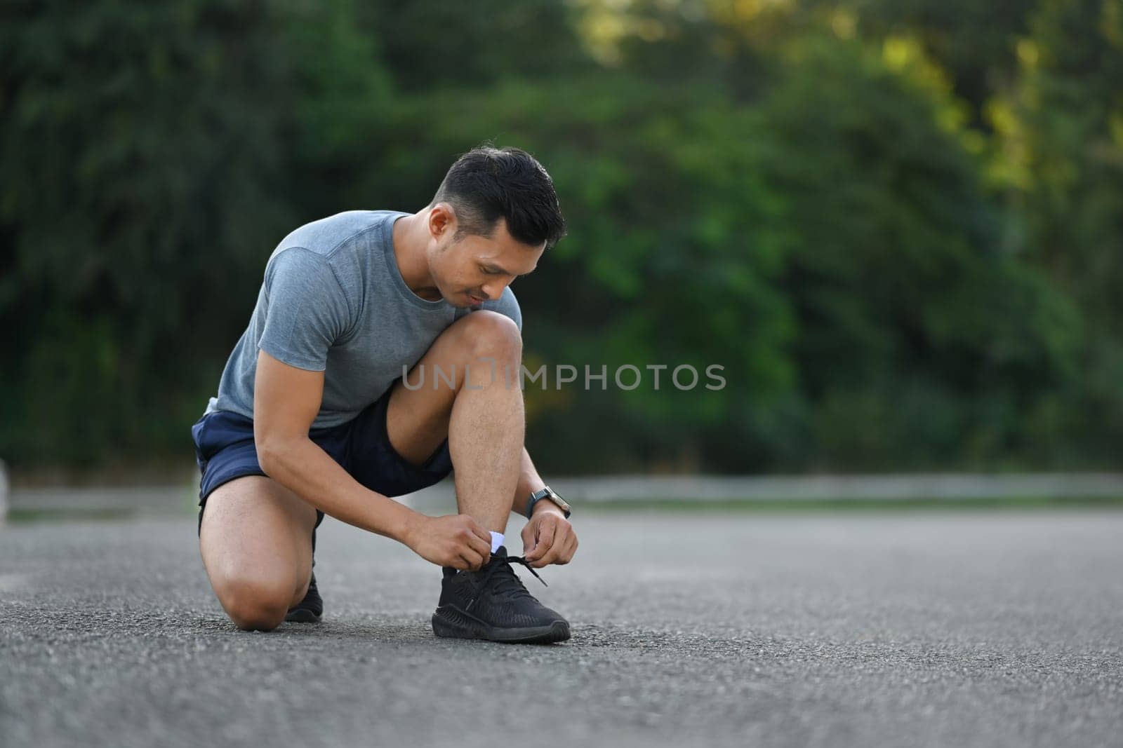 Young sportsman tying shoelace ready for morning jogging. Workout and healthy lifestyle concept.