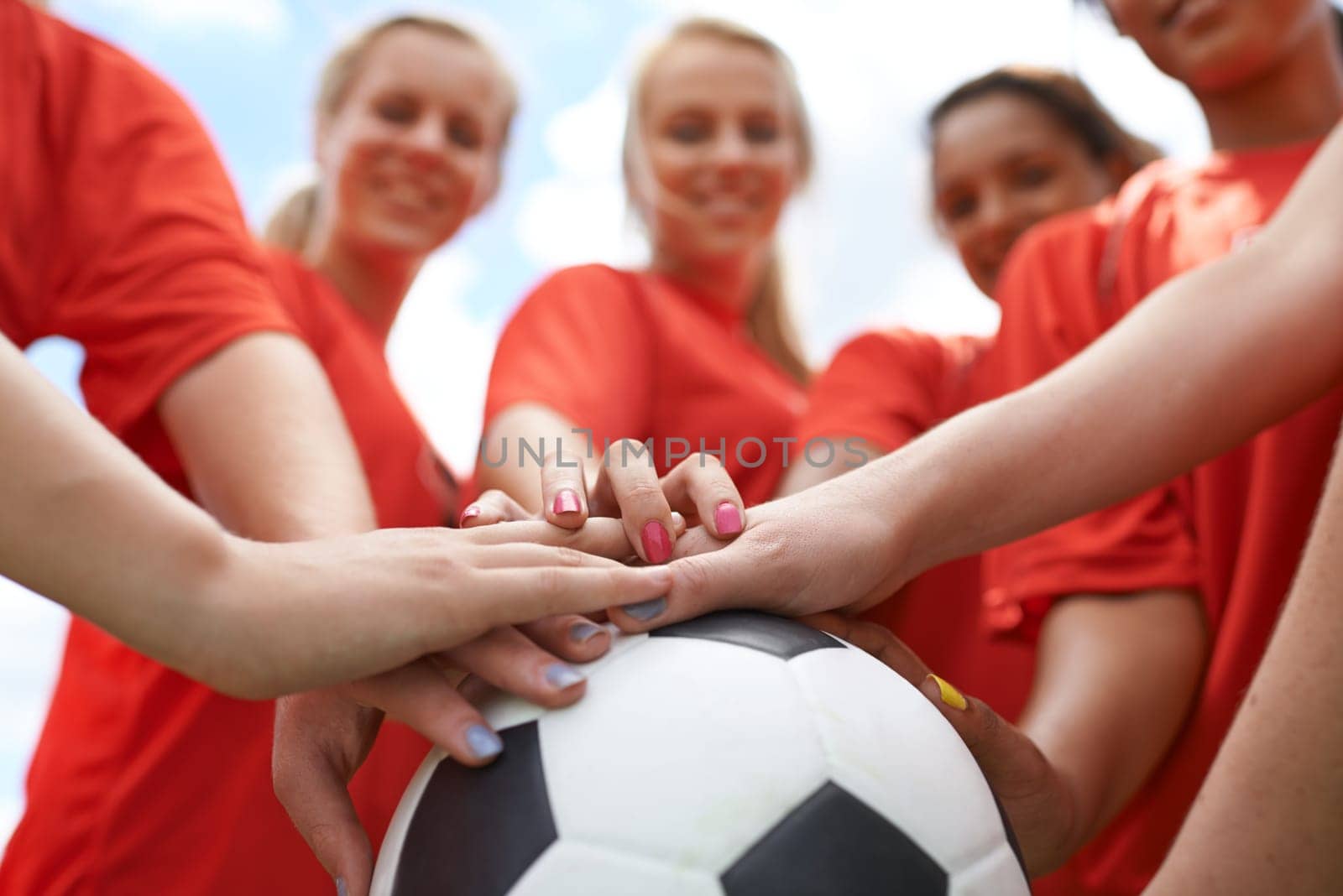 Happy woman, soccer ball and hands together for teamwork, unity or motivation on outdoor field. Closeup of group, people or football players piling in support for sports club, match or game outside.