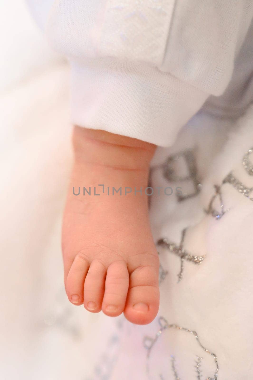 A baby's small leg during baptism on a white sheet, newborn baby.