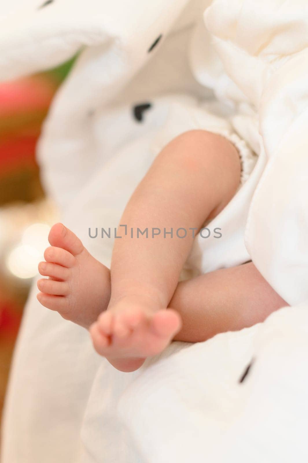 A baby's small leg during baptism on a white sheet. by Niko_Cingaryuk