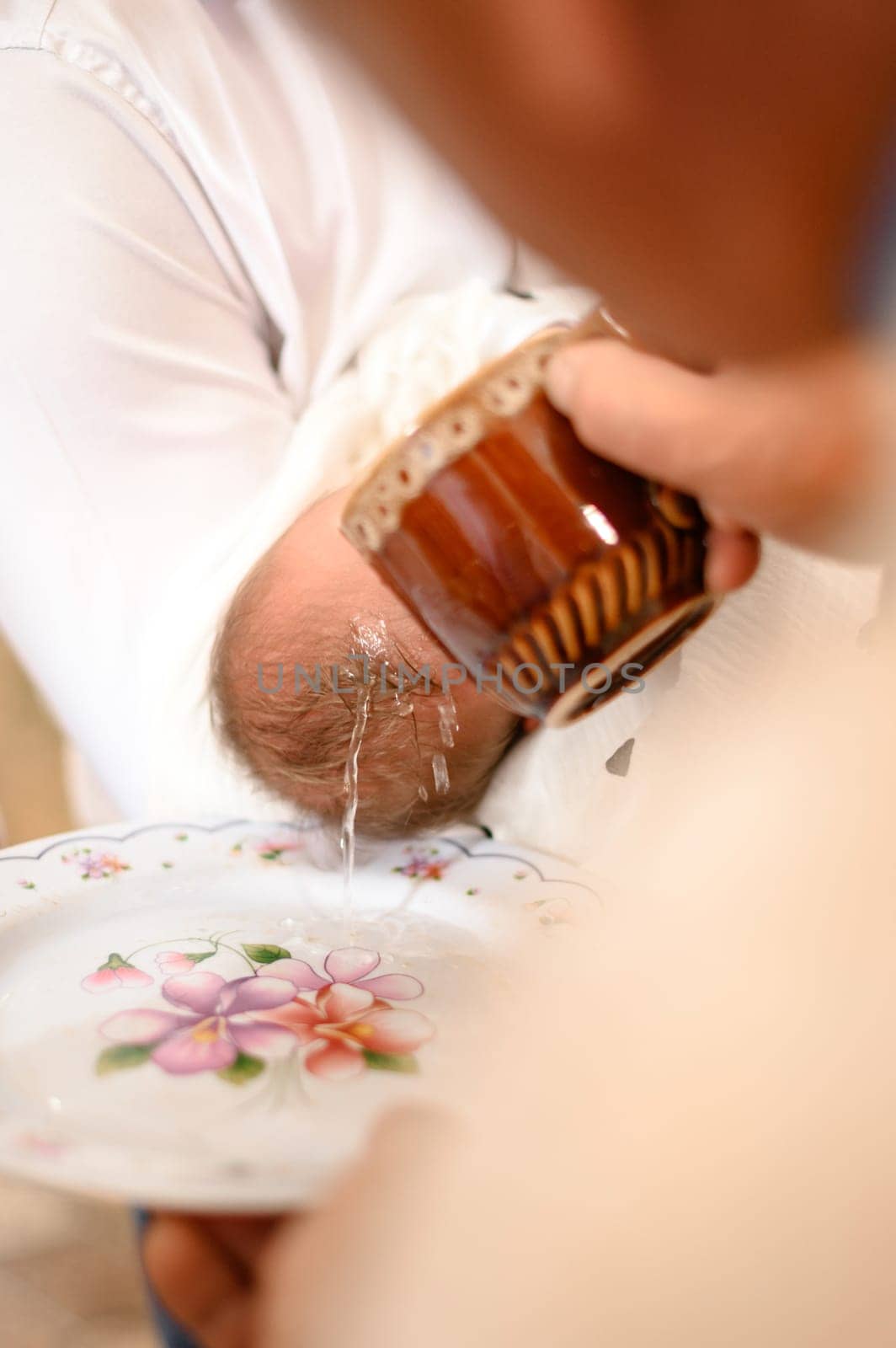 A priest pours water on the head of a small child during the Christian rite of baptism in the church, the baptism of an infant.