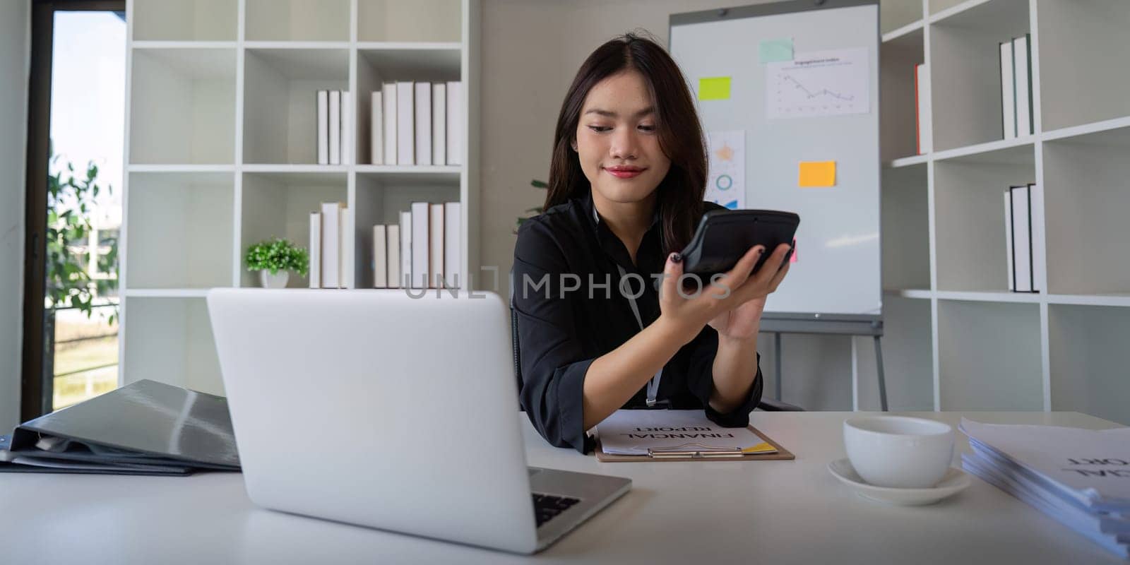 Businesswoman accountant using calculator and laptop for financial data saving in office room, Business financial, tax, accounting concept.