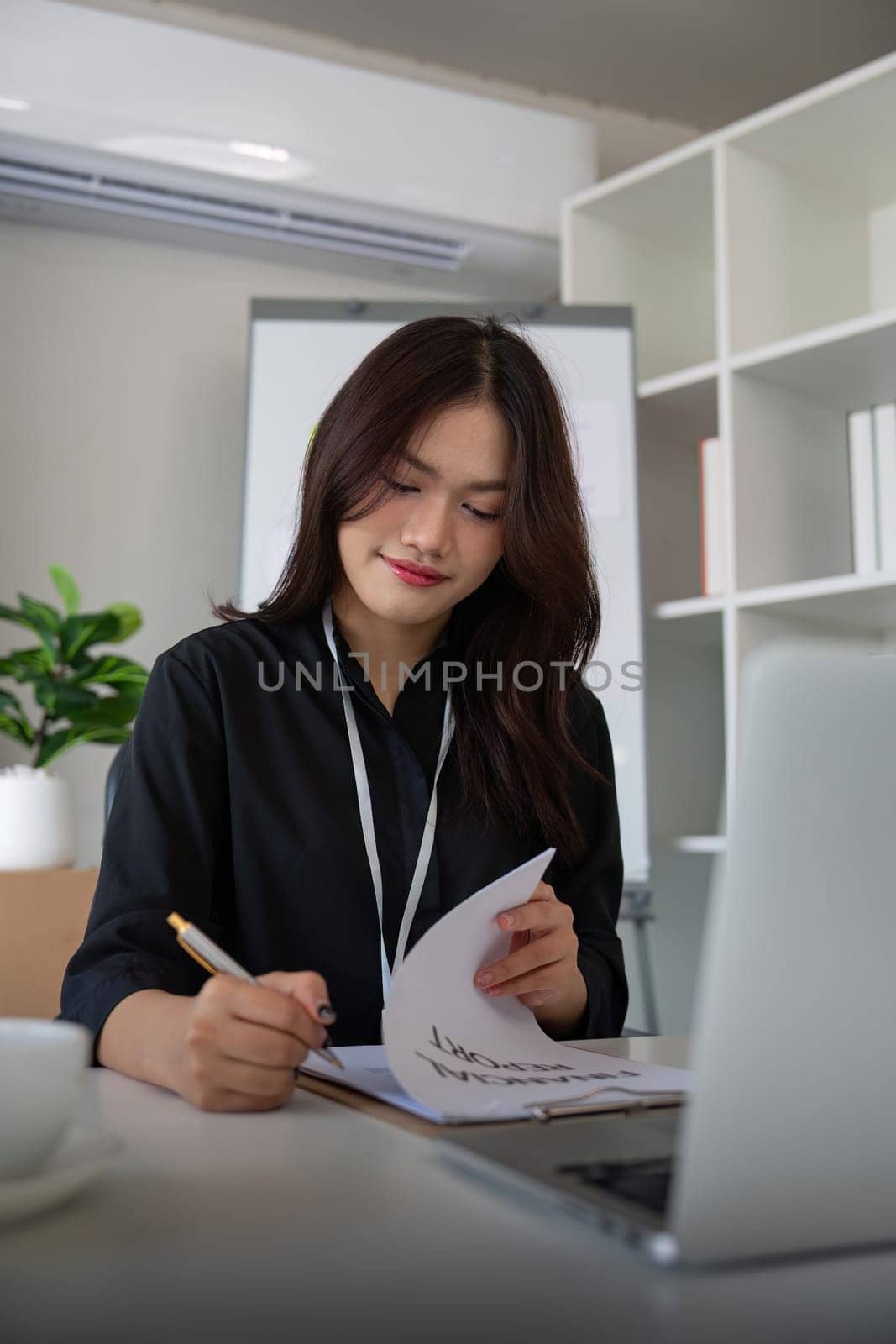 Business analyst hands writing on paperwork, making notes and checking data, chart and graph in an office. Monitoring company growth profit and analyzing document.