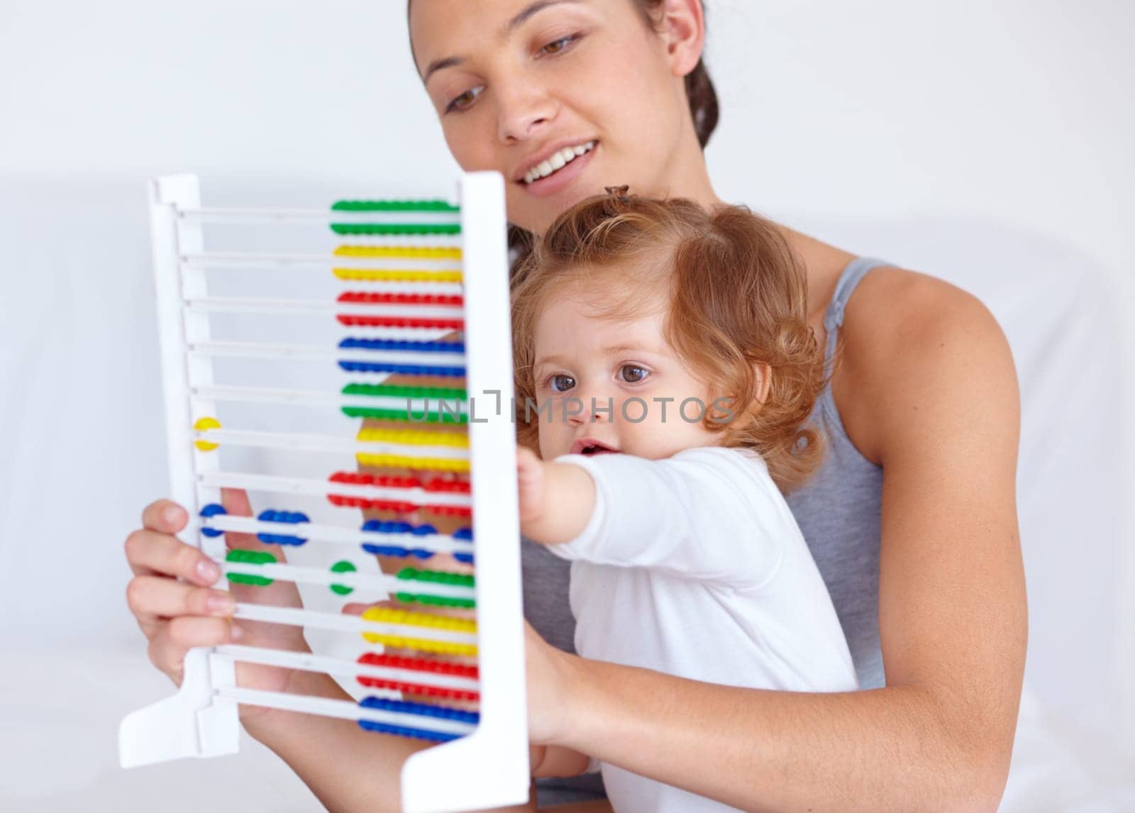 Abacus, playing and girl baby with mother for math, learning and teaching for child development on bed. Bonding, toy and young mom with kid, infant or toddler with counting in bedroom at home