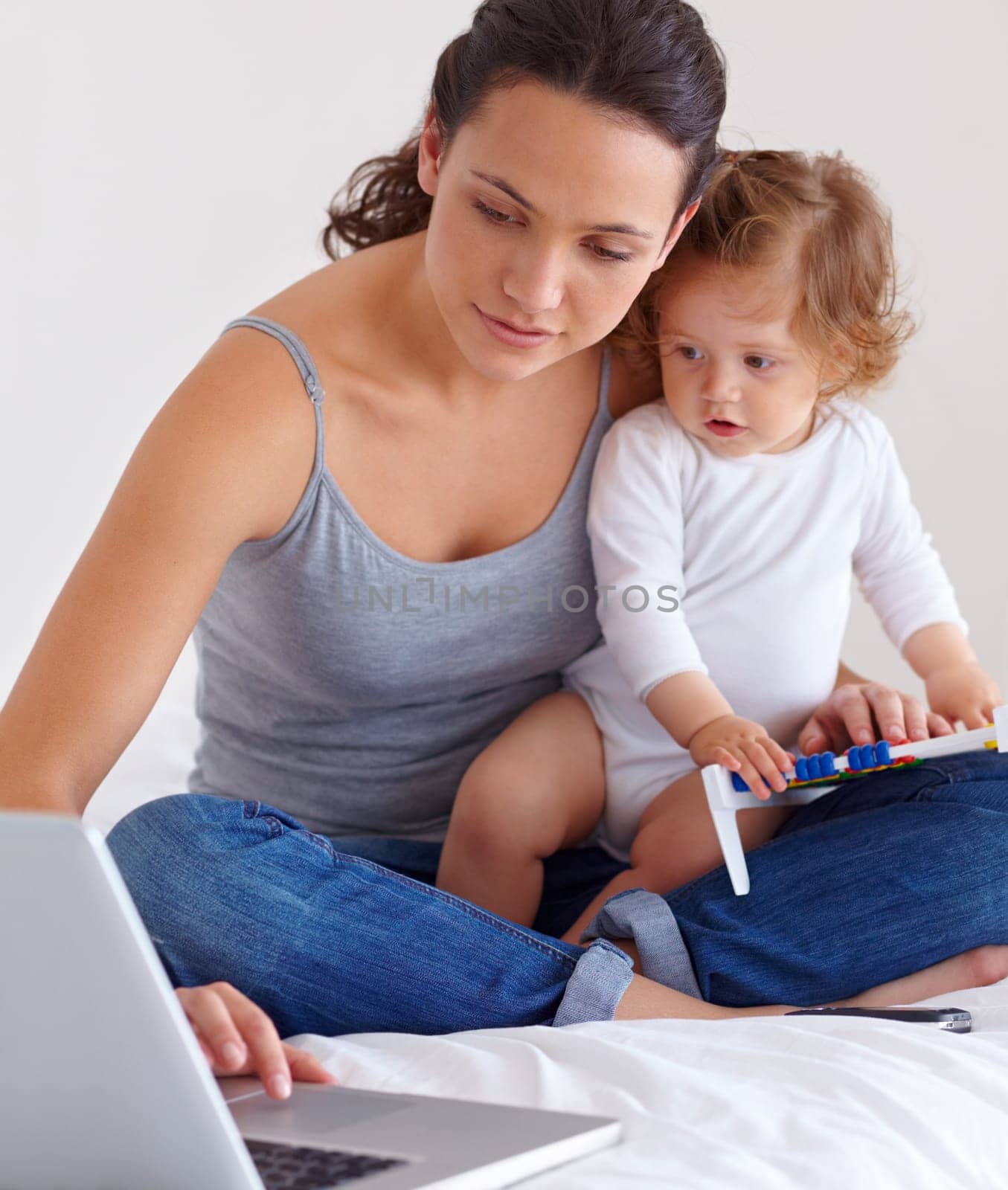 Laptop, baby and mother in bed for remote work, learning or online education in home. Freelancer parent, computer and kid in bedroom playing with abacus, child care and toddler together with family by YuriArcurs