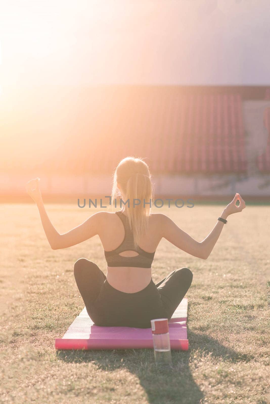 Young female alone at stadium doing yoga by Zelenin