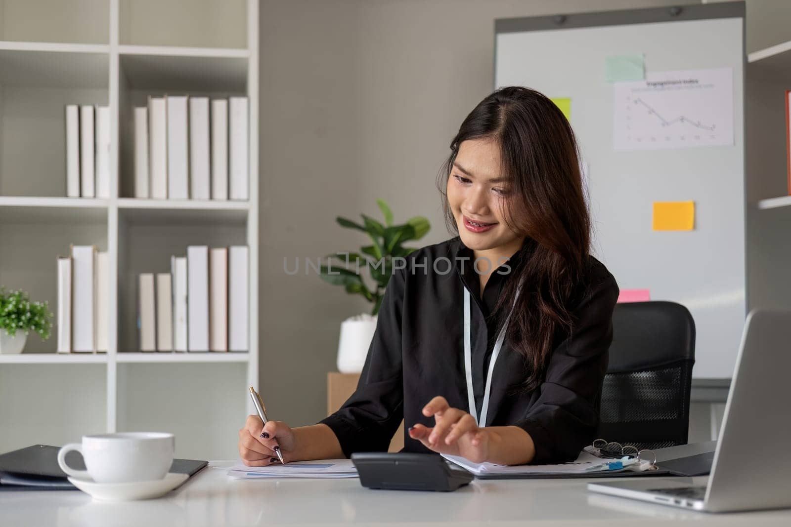 Business woman using calculator and laptop for do math finance on wooden desk in office and business working background, tax, accounting, statistics and analytic research concept.