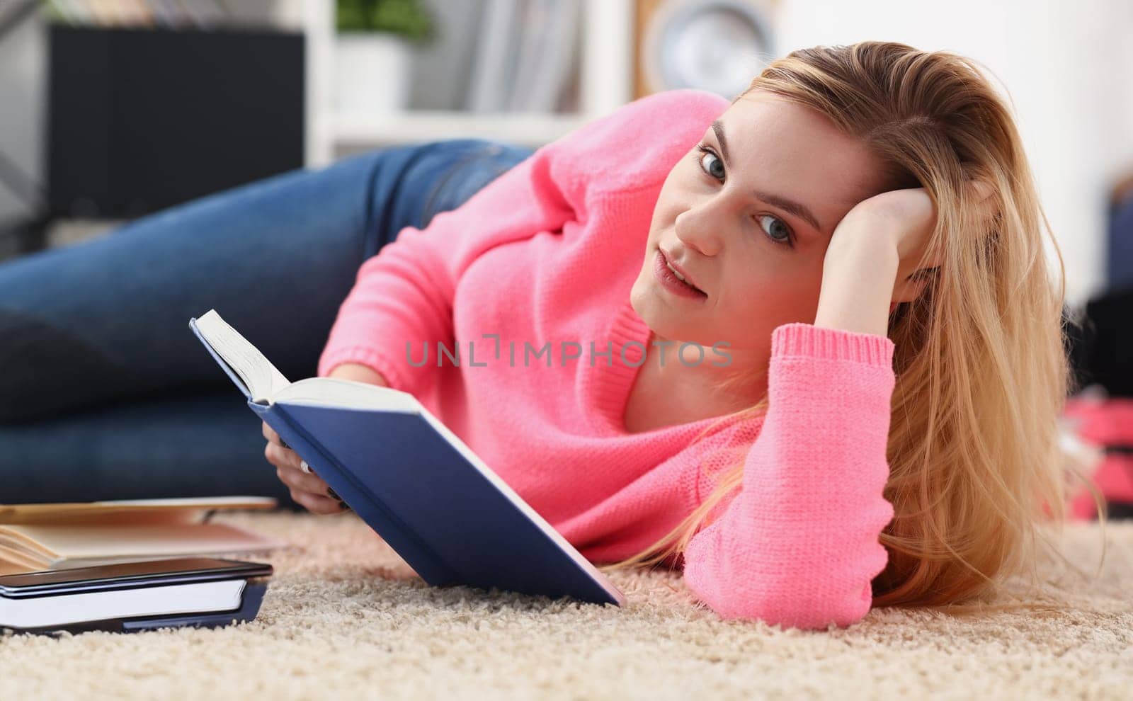 young beautiful blond woman lie on the floor read book by kuprevich