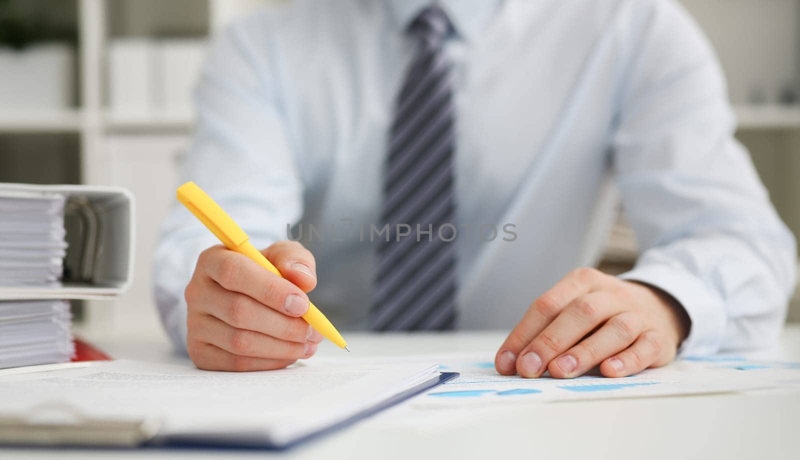 Male hand holding yellow pen ready to make note in opened notebook sheet. Businessman in suit at workspace make thoughts records at personal organizer white collar conference signature concept