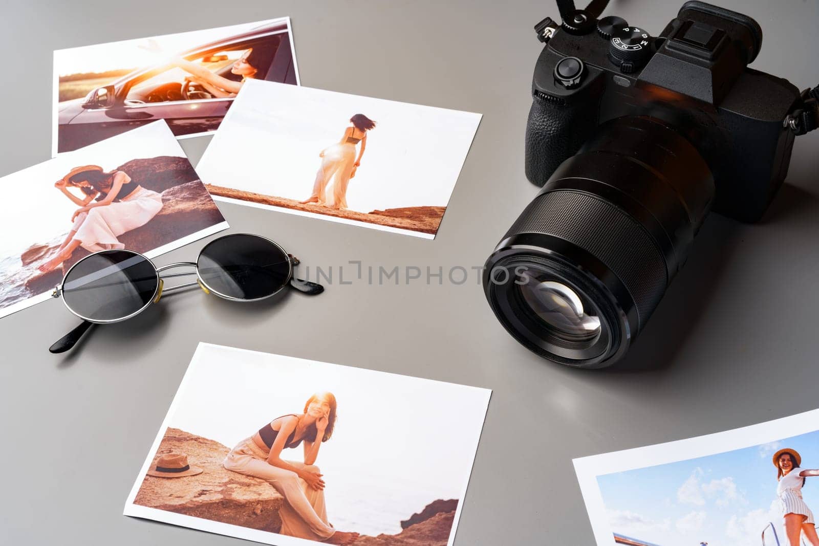 Photo camera with colorful printer photos on gray desk by Fabrikasimf