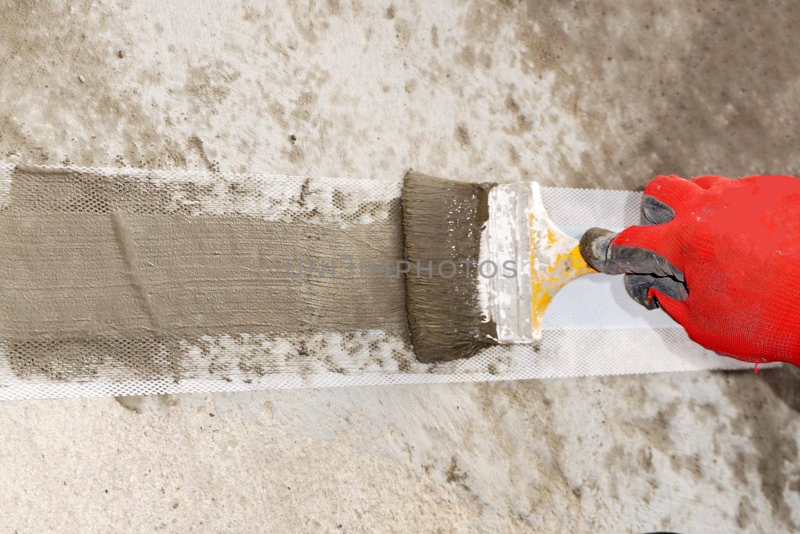 a worker's hand applies a waterproofing solution with a brush to a special waterproofing tape close-up