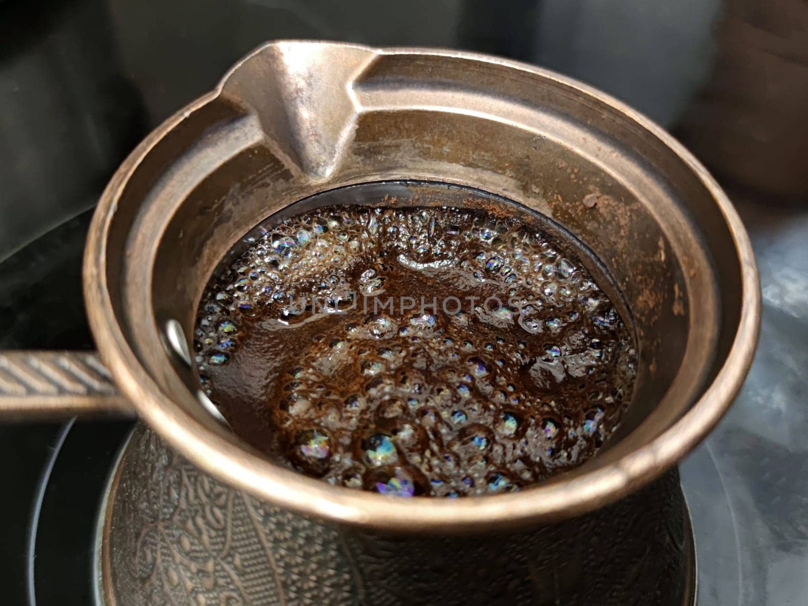 boiling black coffee in a cezve close-up by Annado