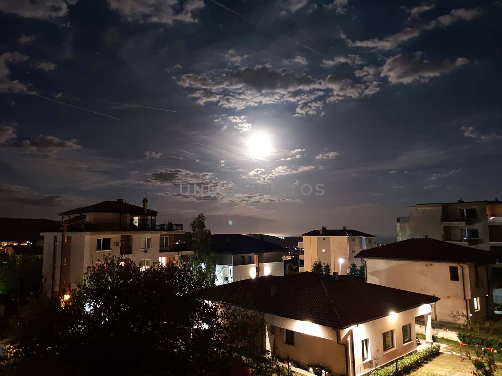 moon in the cloudy night sky above the houses.