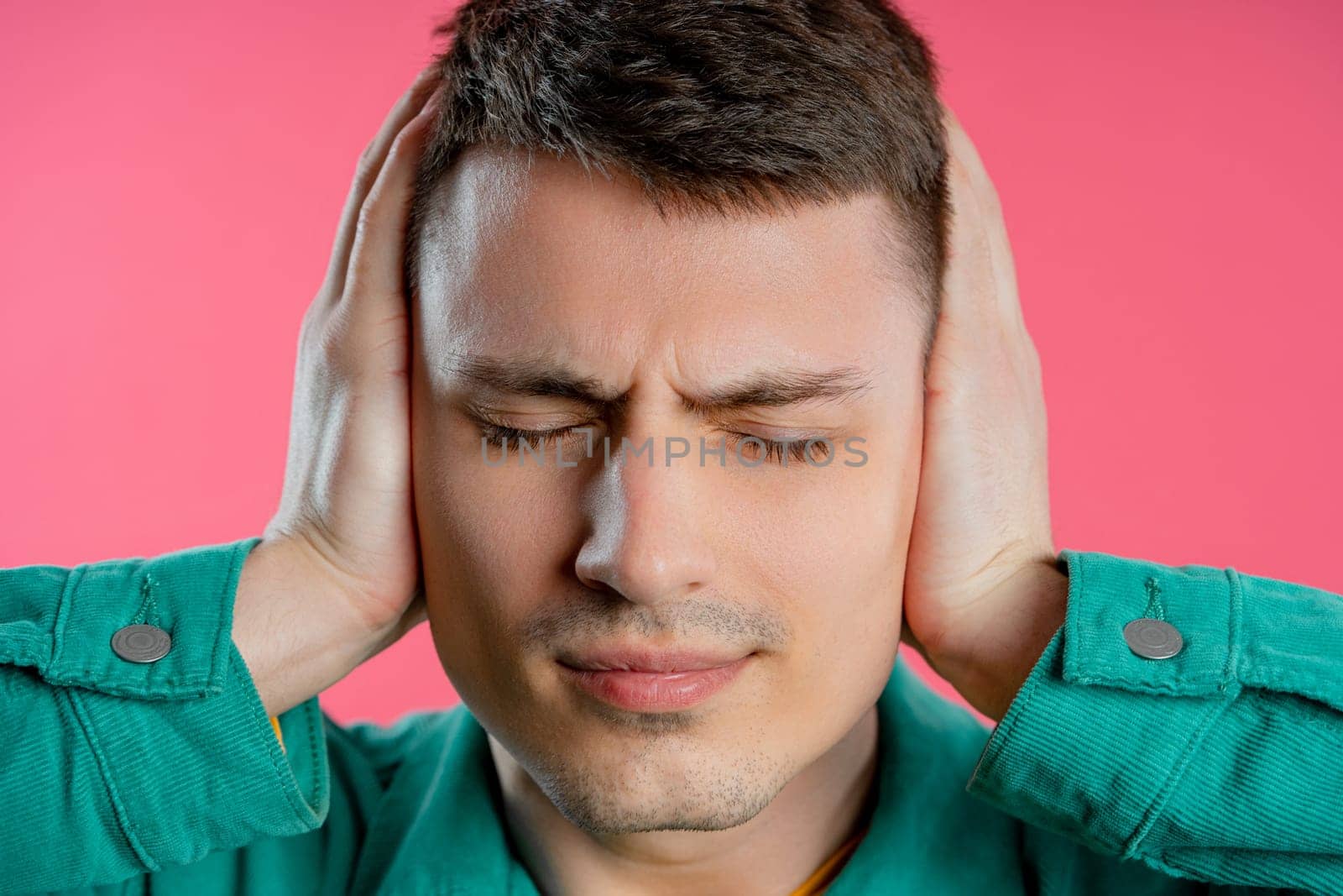 Annoyed man with shut ears on pink background. Guy block annoying sounds by kristina_kokhanova