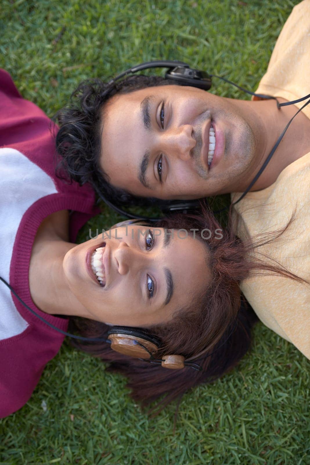 Students, portrait and grass or headphones for music listening from above for entertainment, education or relax. Man, woman and friends or face on university campus or podcast, streaming or knowledge by YuriArcurs