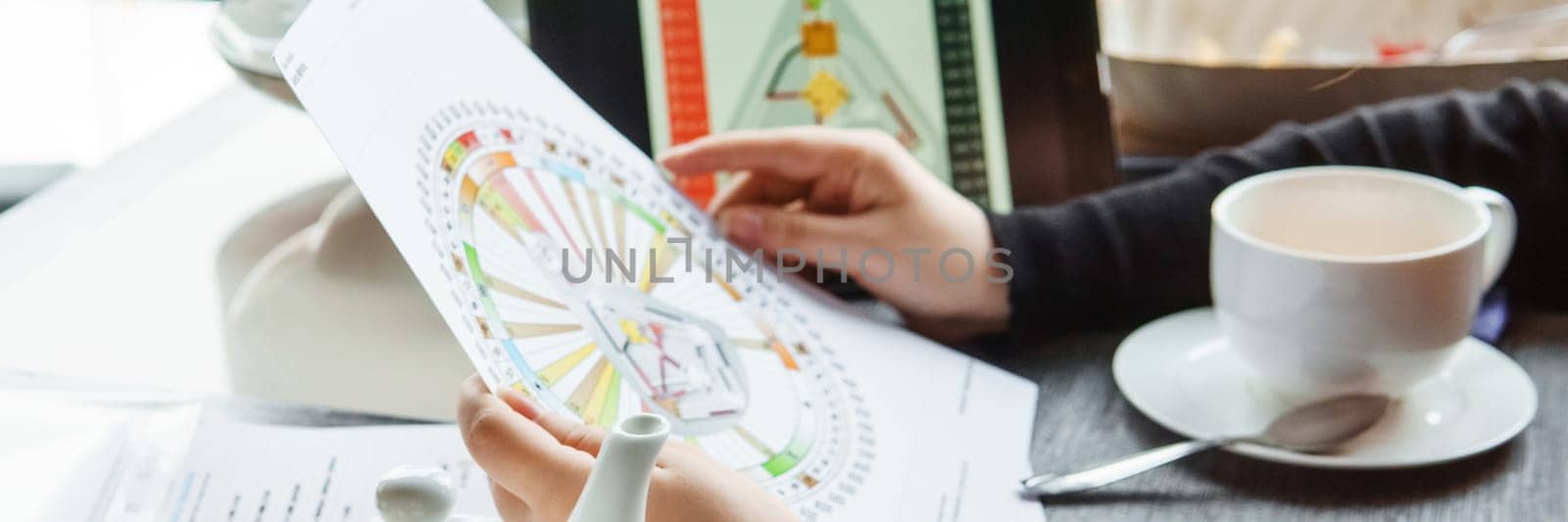 TVER, RUSSIA - FEBRUARY 12, 2023: A woman at the table is studying a rave mandala by human design. Rave mandala on the table close-up. The concept of esoteric teachings