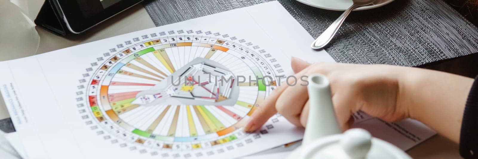 TVER, RUSSIA - FEBRUARY 12, 2023: A woman at the table is studying a rave mandala by human design. Rave mandala on the table close-up. The concept of esoteric teachings. by Annu1tochka