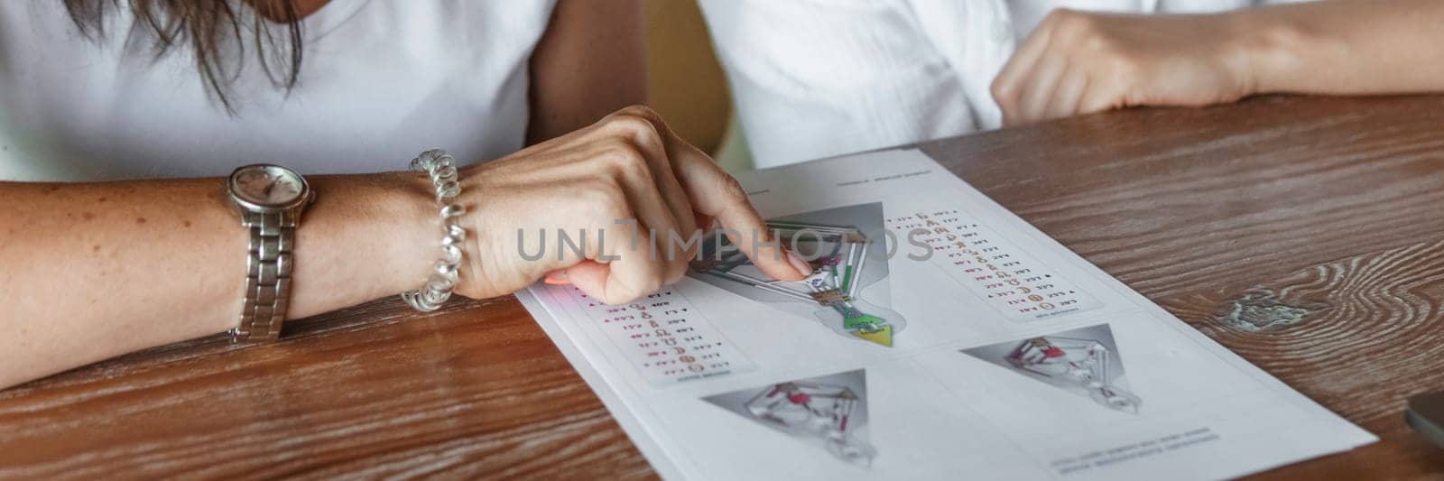 Tver, Russia - August 2, 2021. A woman in a cafe at a table is studying the design of a person. The concept of studying esoteric sciences. A bodigraph or a map of a person on an A4 sheet. by Annu1tochka