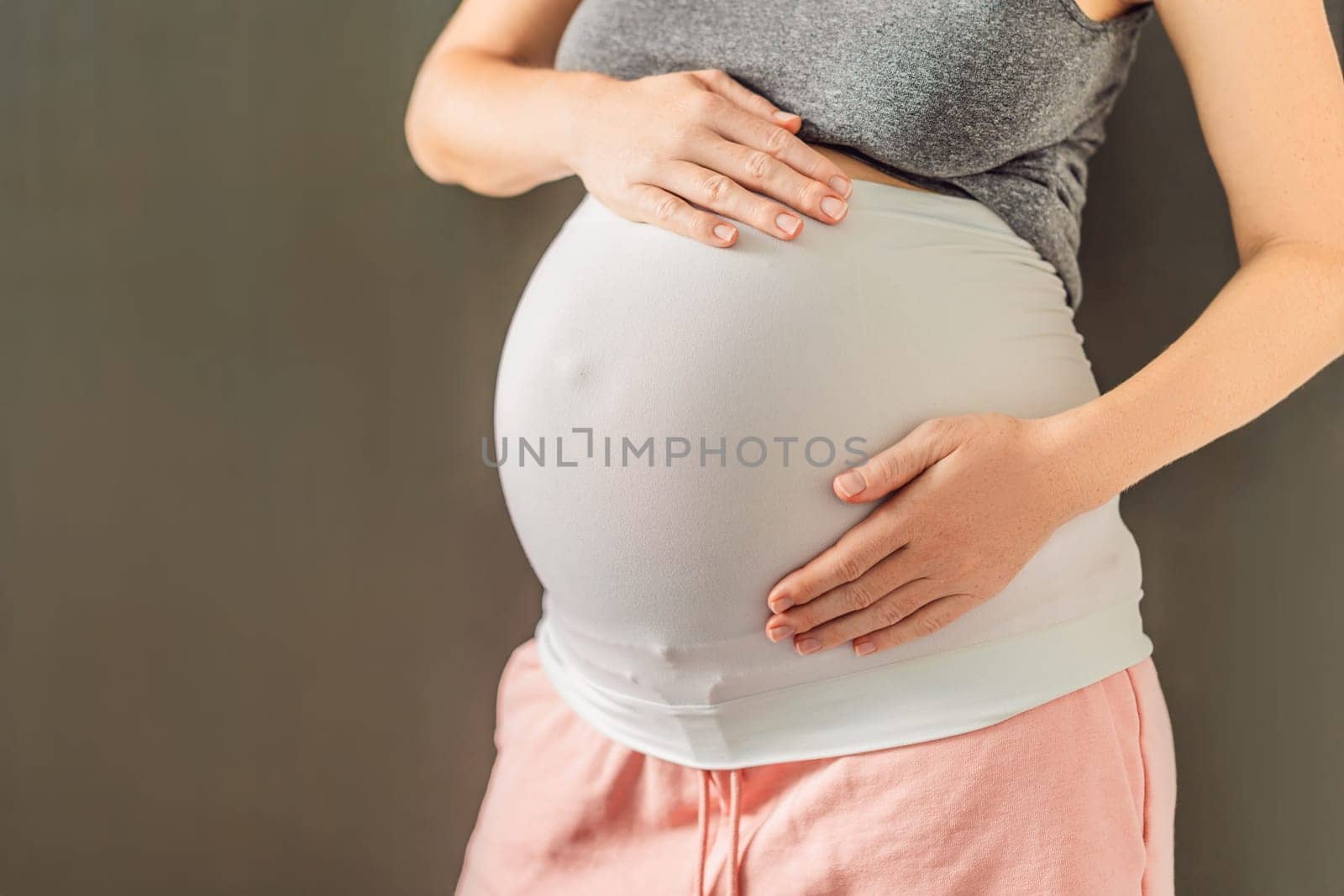 Pregnant bliss: Mom-to-be embraces her baby bump with a soft fabric bandage, providing gentle support. Maternity made comfortable.