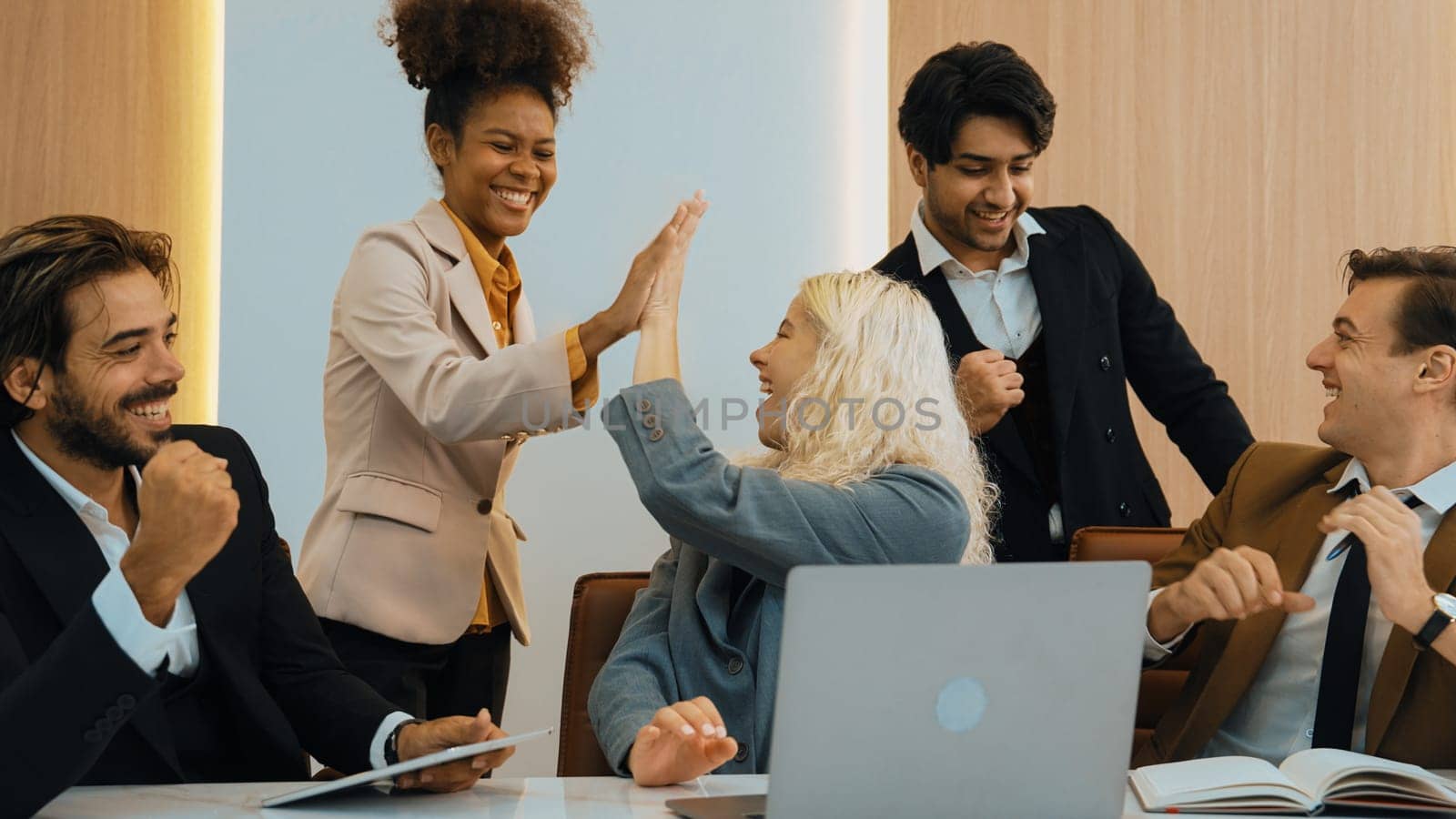 Diverse group of office worker and employee raise their hands up with happy and excited celebration for being good teamwork and positive attitude contribute to business success in ornamented workplace