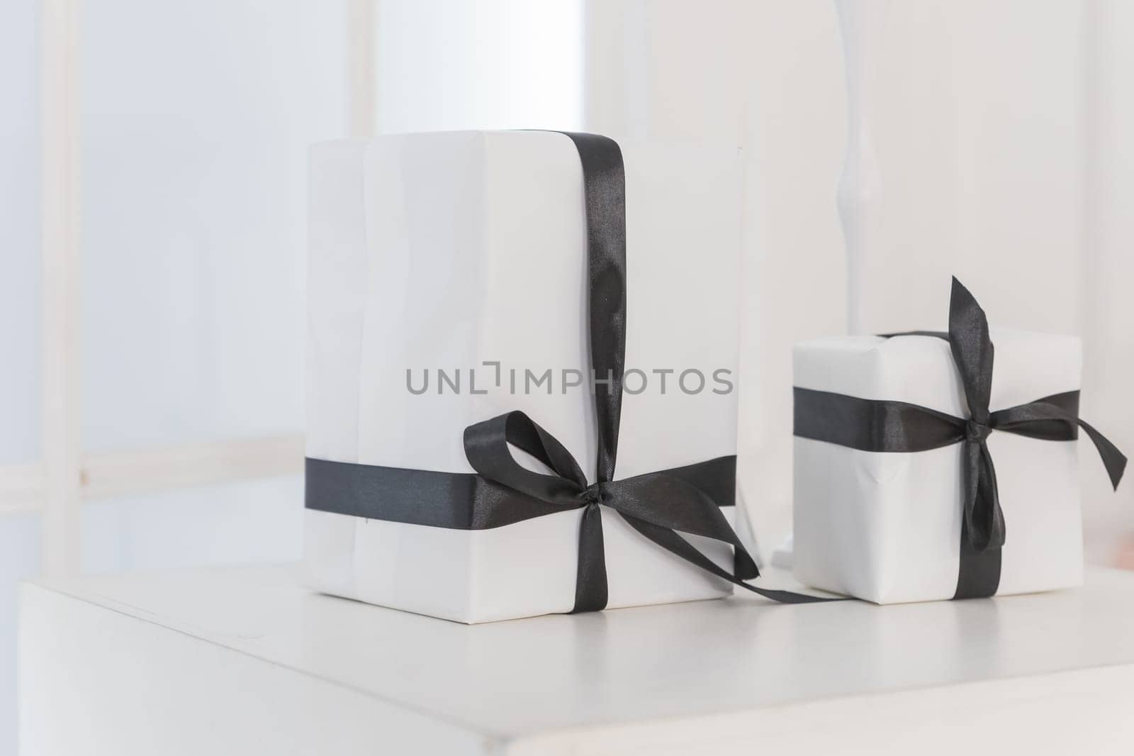 Packaging box studio shot of white boxes wrapping with black ribbon with bowknot on white background. Black Friday sale. shop sale promotion and anniversary celebration concept by YuliaYaspe1979