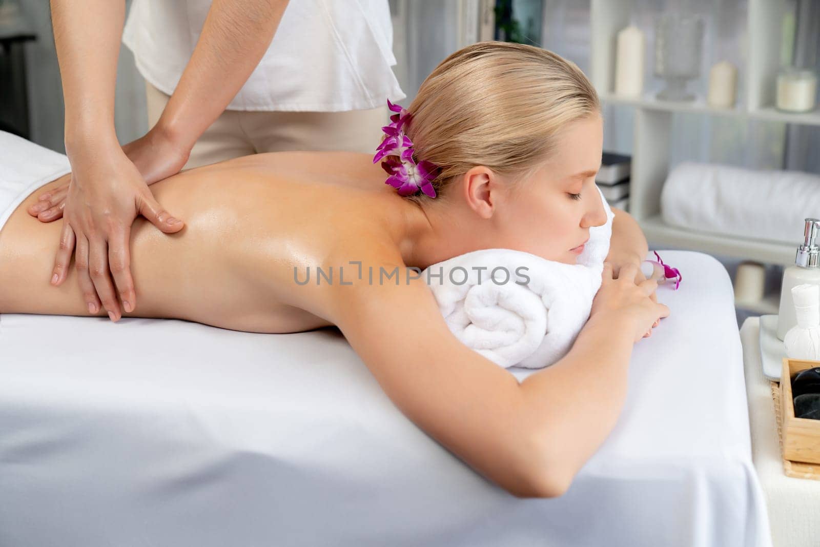 Caucasian woman customer enjoying relaxing anti-stress spa massage and pampering with beauty skin recreation leisure in day light ambient salon spa at luxury resort or hotel. Quiescent