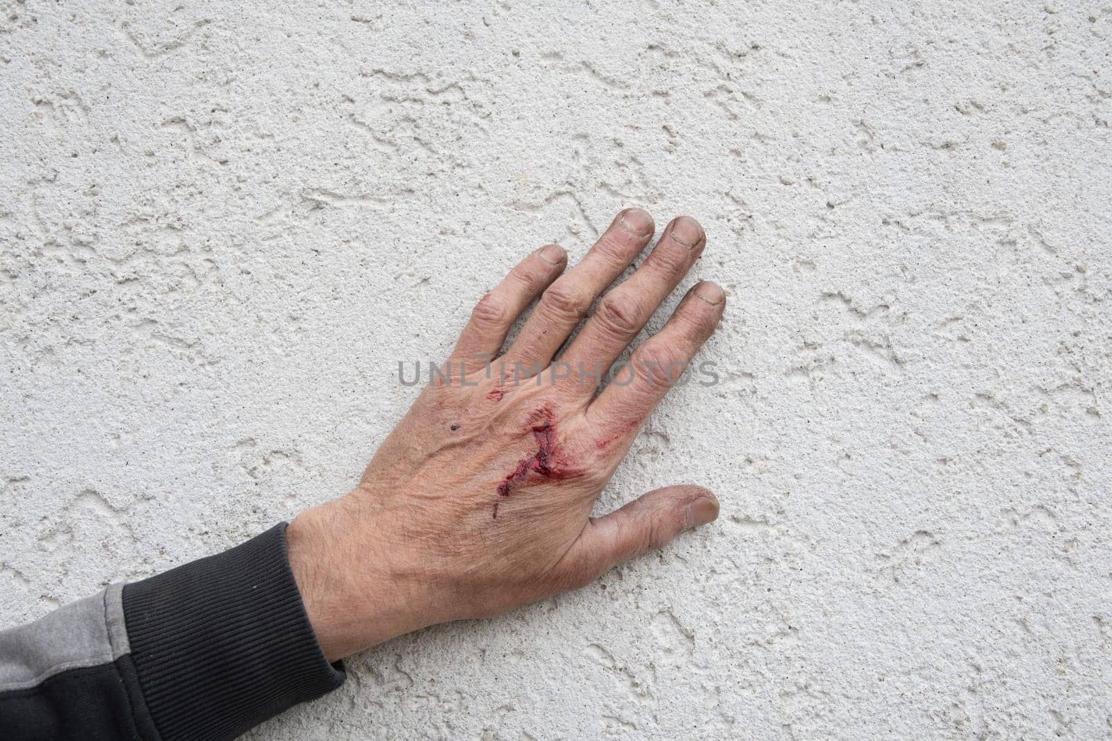 bloody and dirty left hand of a working man from the back, male worker by KaterinaDalemans