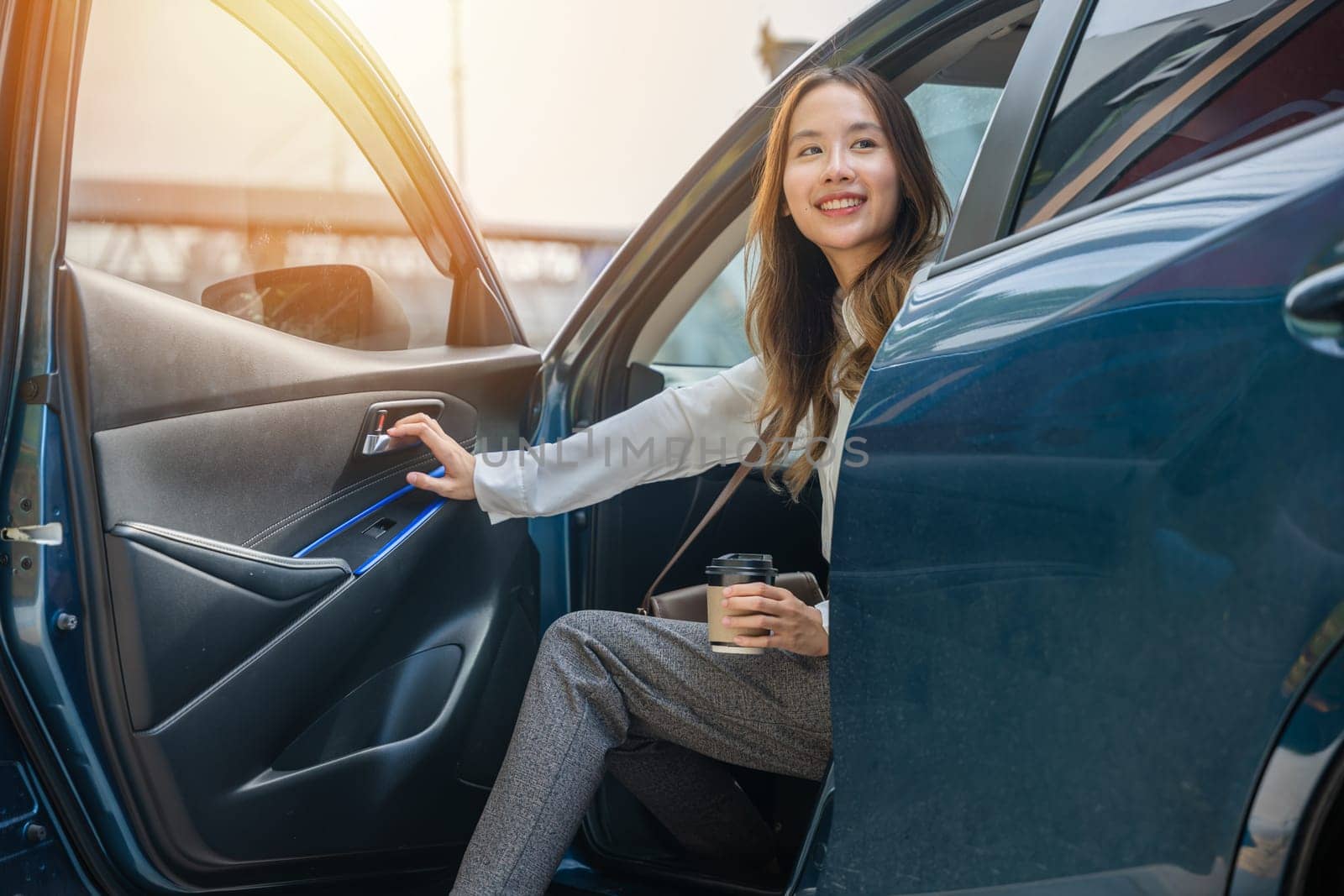 A corporate employee elegant in a business suit sits in a luxurious car. Her long slender leg graced with high heels opens the door symbolizing the transition from luxury driving to business pursuits.
