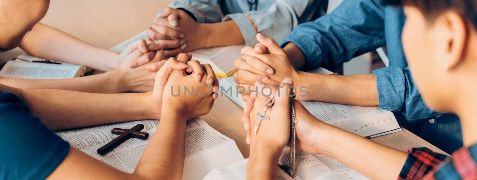 Cropped image of diversity people hand praying together at wooden church on bible book while hold hand together with believe. Concept of hope, religion, faith, god blessing concept. Burgeoning.