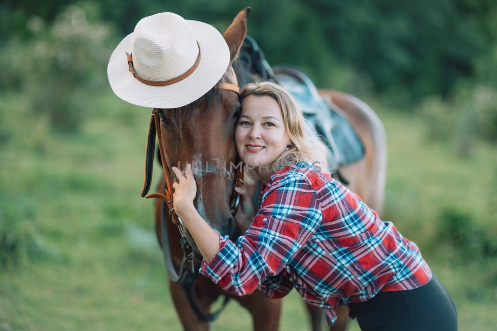 Happy blonde with horse in forest. Woman and a horse walking through the field during the day. Dressed in a plaid shirt and black leggings. by Matiunina