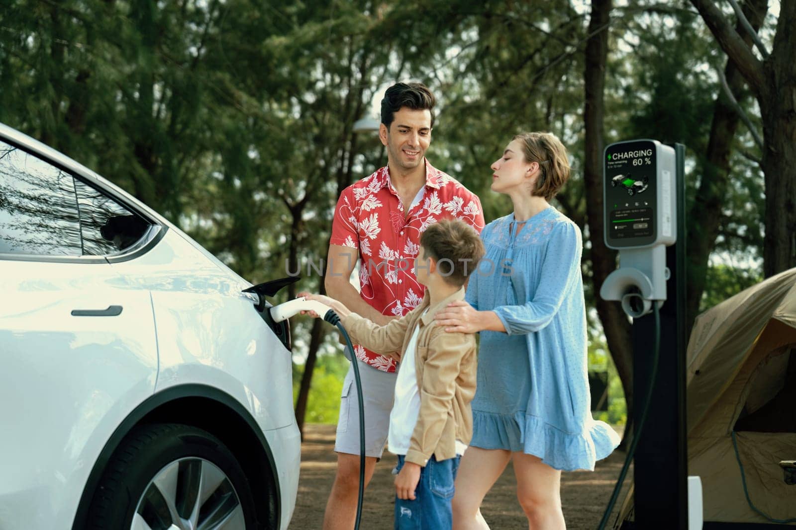 Lovely family recharge EV car with EV charging station in campsite. Perpetual by biancoblue