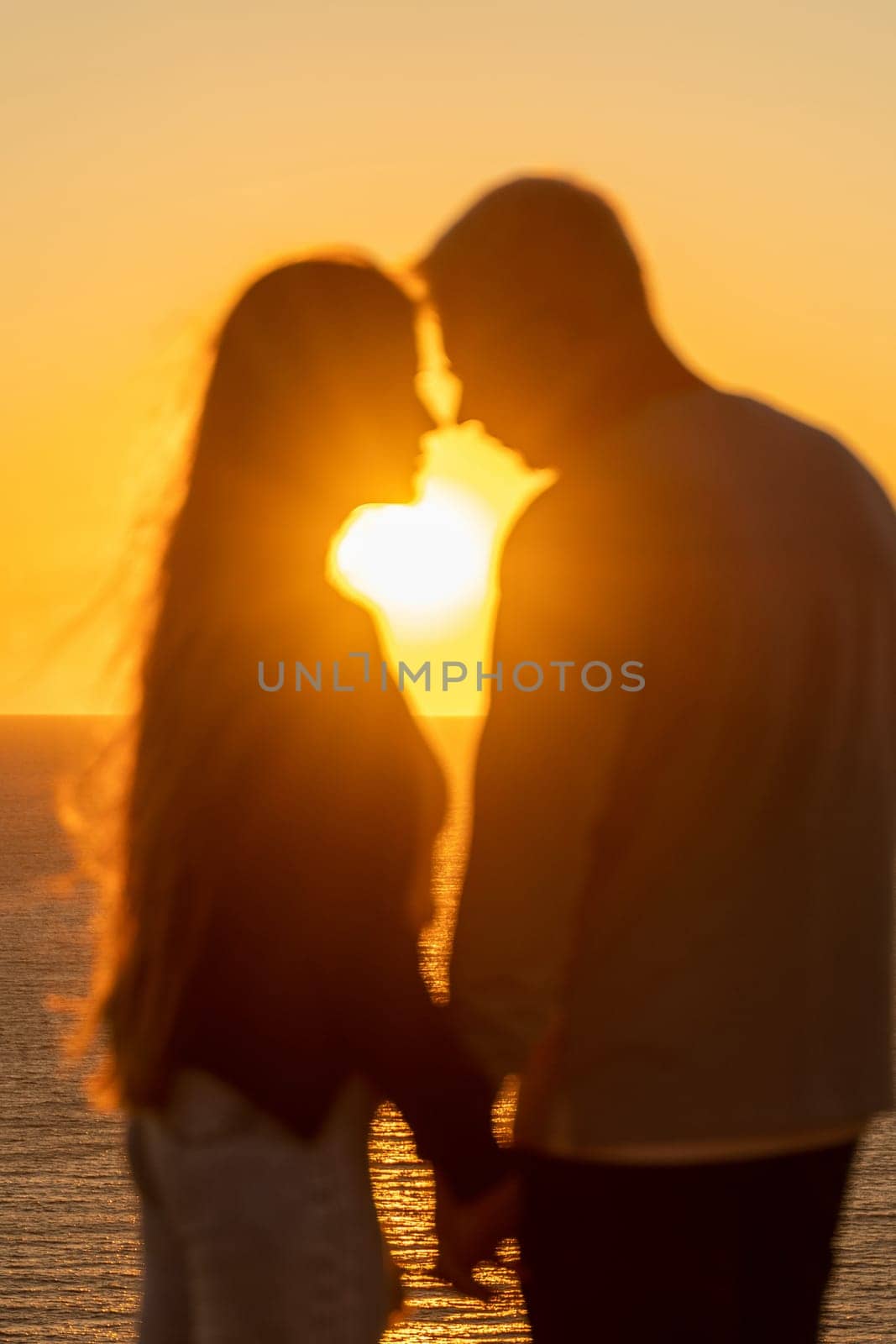 At sunset, a couple shares a tender embrace on the beach, basking in the tranquility of their holiday and the beauty of nature. by Matiunina