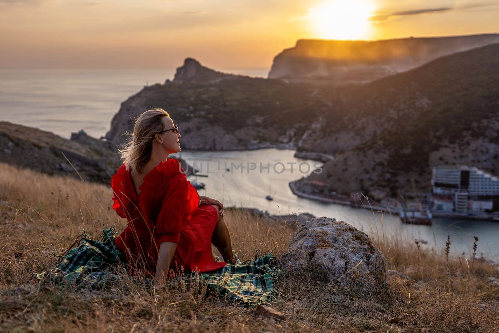 Woman sunset sea mountains. Happy woman siting with her back on the sunset in nature summer posing with mountains on sunset, silhouette. Woman in the mountains red dress, eco friendly, summer landscape active rest by Matiunina