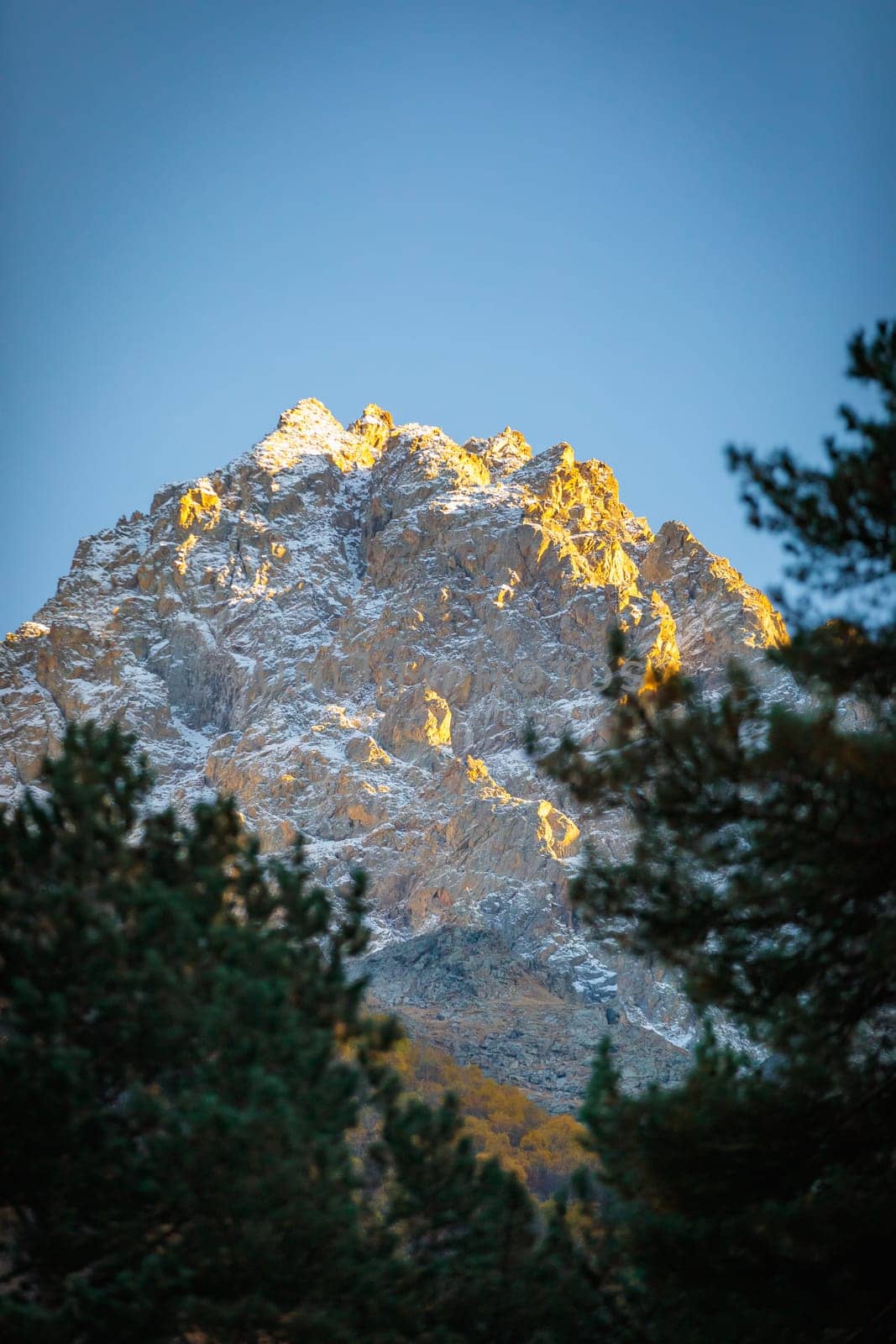 A majestic snow-capped mountain peak bathed by the sunset rays