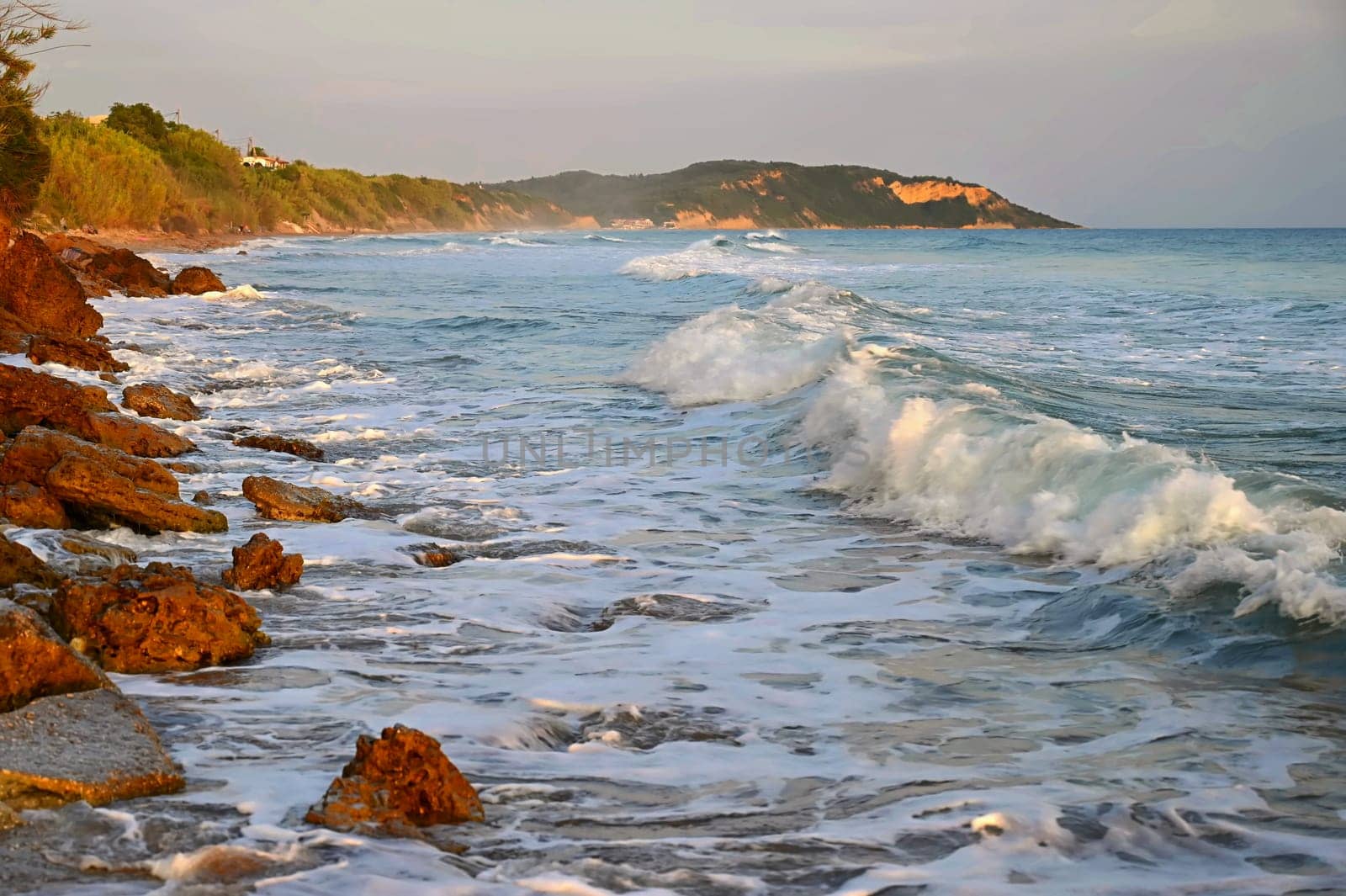 Sea at sunset with waves on the beach. Greece - the island of Corfu. by Montypeter