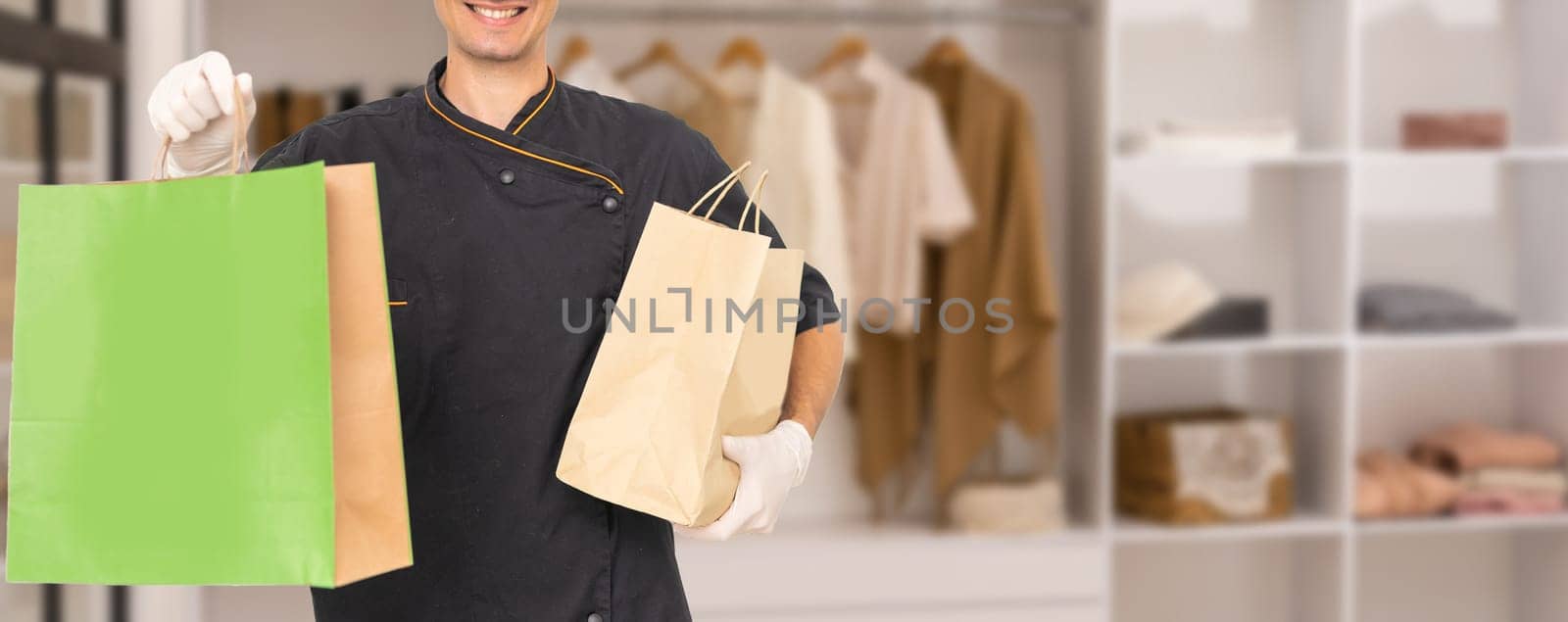 Paper pocket and food containers in hands of a smiling deliveryman. .Quality service of a restaurant