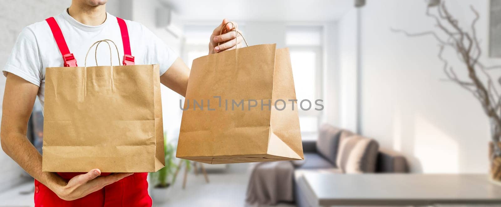 Courier holding paper bags with food, space for text. Delivery service by Andelov13
