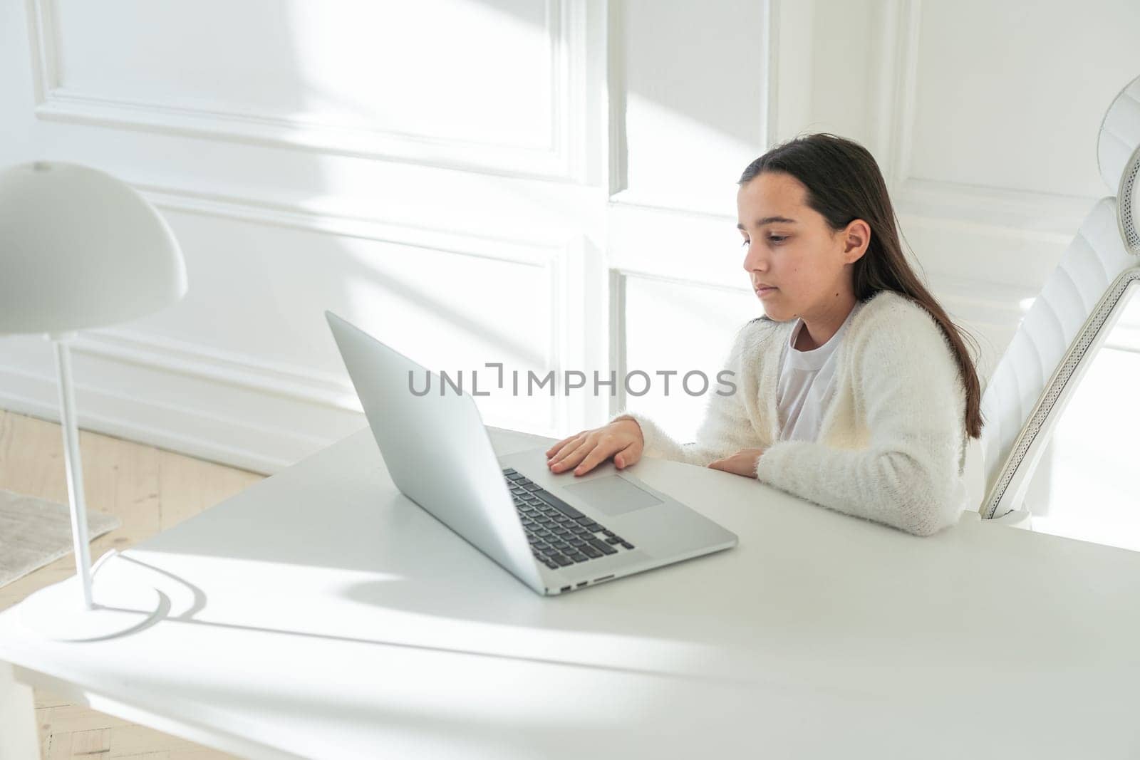 Online School. Happy Schoolgirl At Laptop Learning And Gesturing Thumbs Up To Camera, Approving Great Online Lesson And Educational Offer Posing At Home, Sitting At Table Indoor by Andelov13