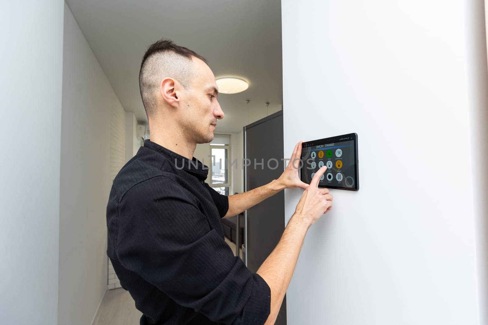 Man using smart home security system control panel by Andelov13