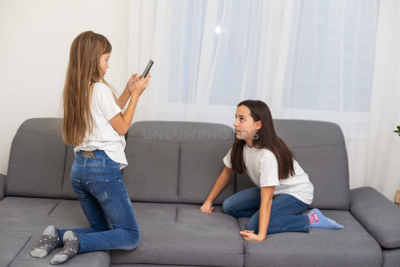 people, technology and friendship concept - happy teenage girls taking selfie with smartphone sitting on sofa at home. High quality photo