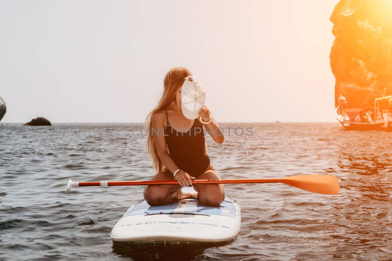 Close up shot of beautiful young caucasian woman with black hair and freckles looking at camera and smiling. Cute woman portrait in a pink bikini posing on a volcanic rock high above the sea