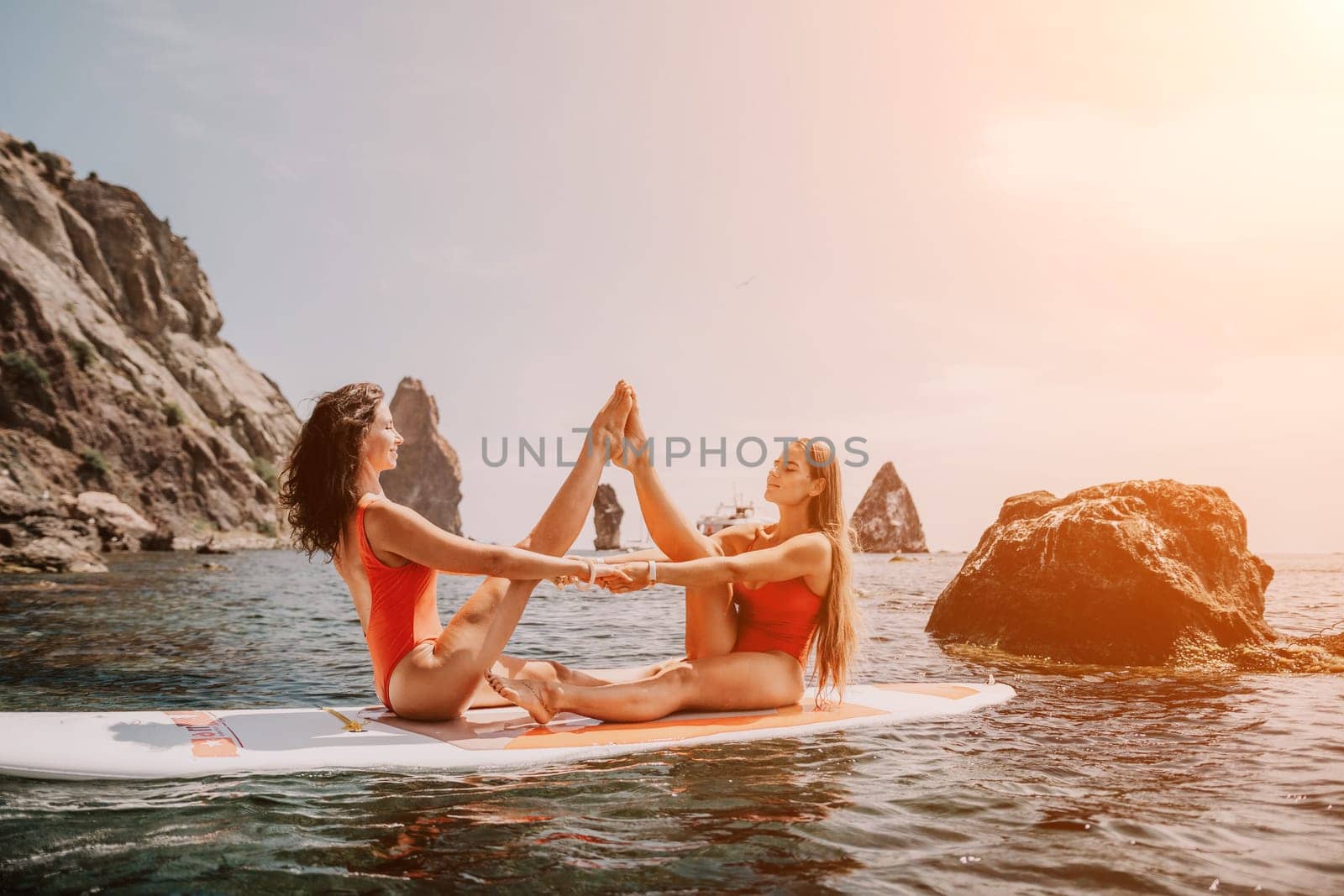 Woman sup yoga. Middle age sporty woman practising yoga pilates on paddle sup surfboard. Female stretching doing workout on sea water. Modern individual hipster outdoor summer sport activity