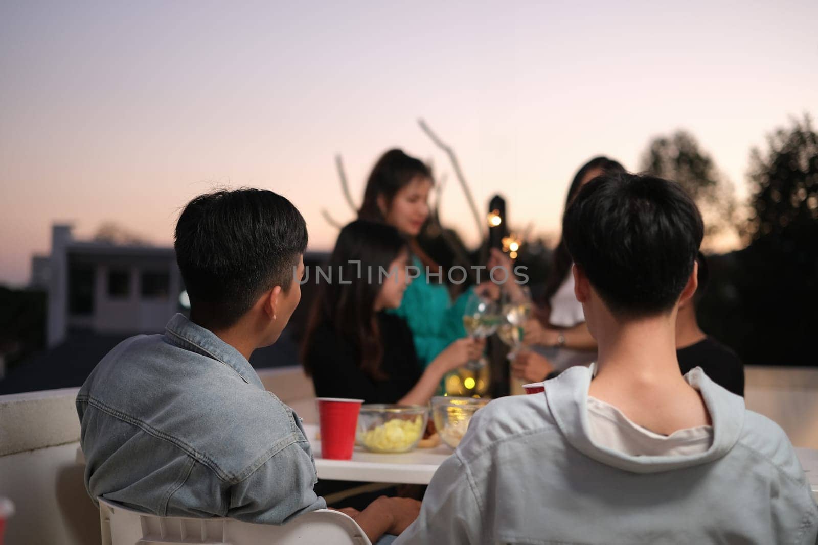 Male and female friends talking and sharing nice moments together at the rooftop party.