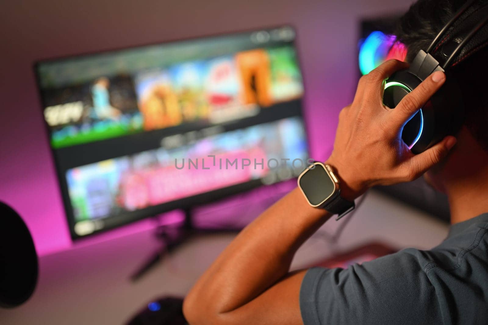 Cropped shot pro gamer wearing headset playing online video game on his personal computer at home.