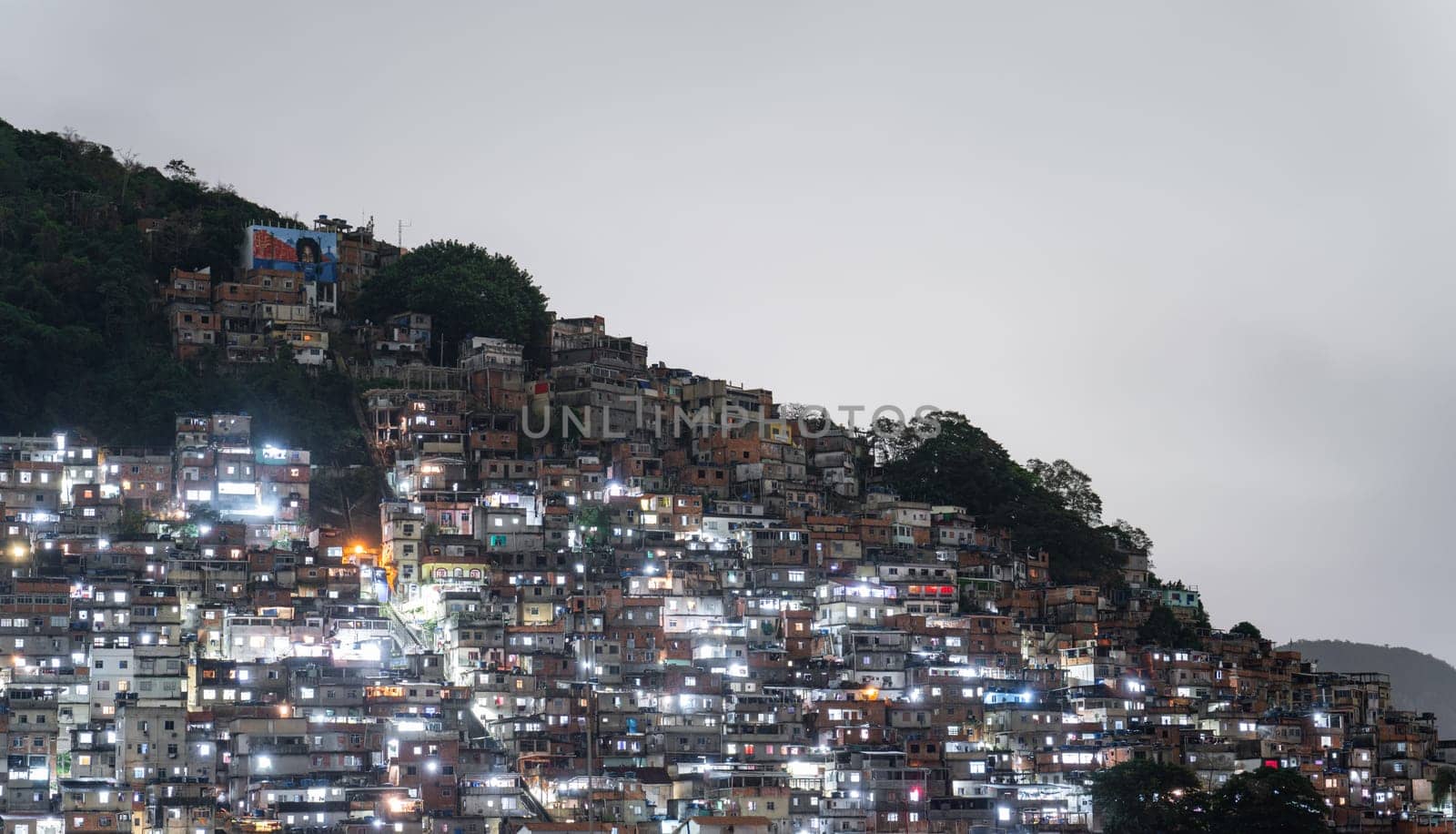 Night View of Dense Hillside Favela in Urban Brazil by FerradalFCG