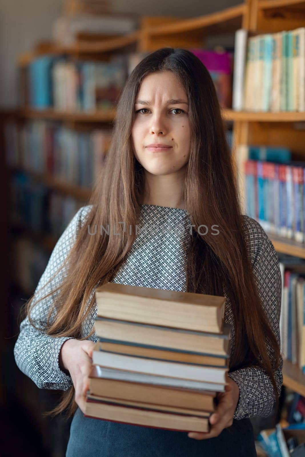 Young brunette girl holding books with confused facial expression by VitaliiPetrushenko