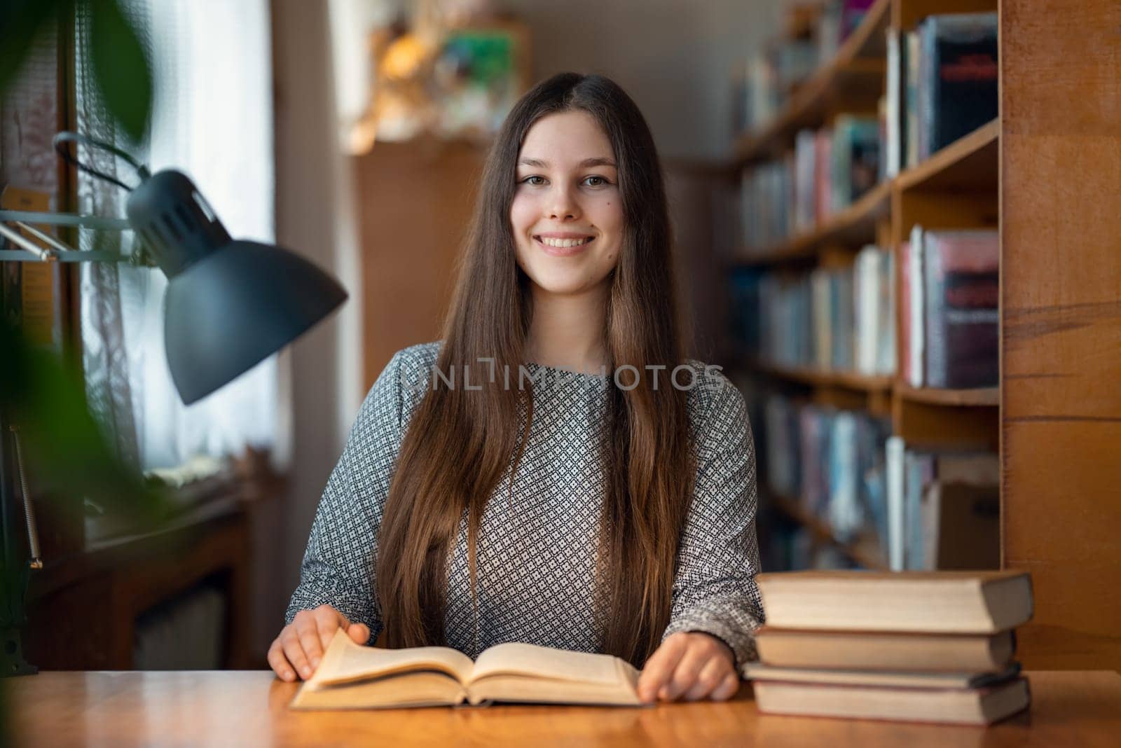 Brunette girl with long hair enjoys studying time at the library, getting education with pleasure