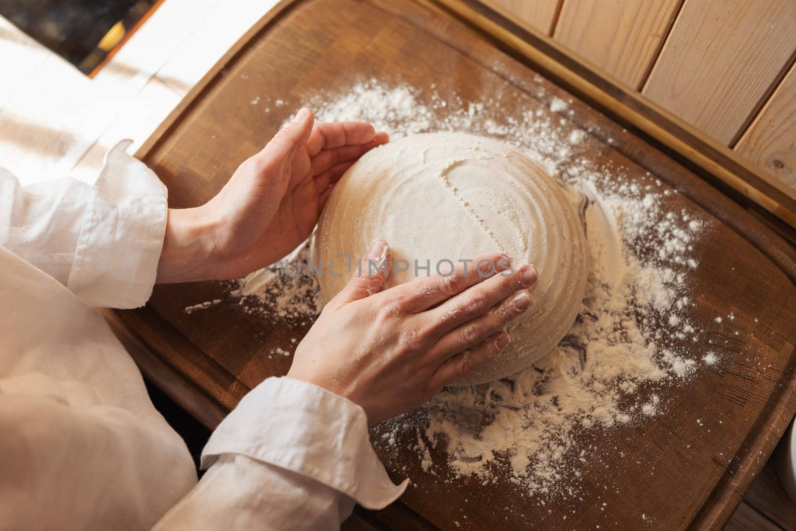 Woman sprinkle a dough with flour, making form for a bread loaf by VitaliiPetrushenko